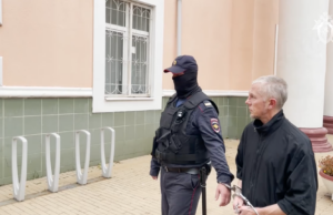 Мужчина, обвиненный в изнасилованиях и убийствах девушек 20-летней давности, в сопровождении сотрудника полиции - РИА Новости, 1920, 28.03.2026