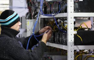 Сотрудник возле стеллажей с фермами для майнинга криптовалют - РИА Новости, 1920, 14.04.2026