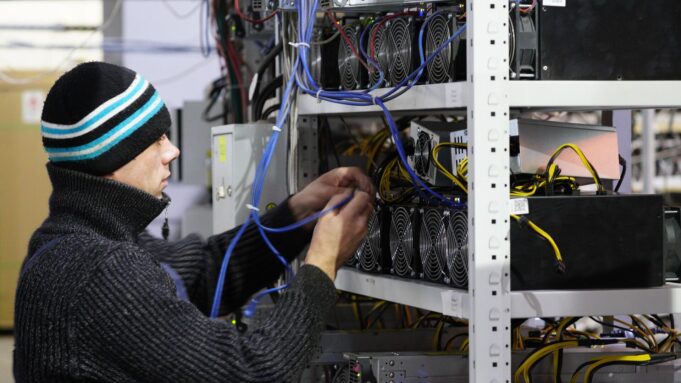 Сотрудник возле стеллажей с фермами для майнинга криптовалют - РИА Новости, 1920, 14.04.2026